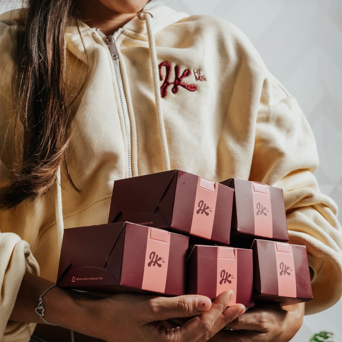 Una persona lleva en brazos varias cajas de Hi Milk
